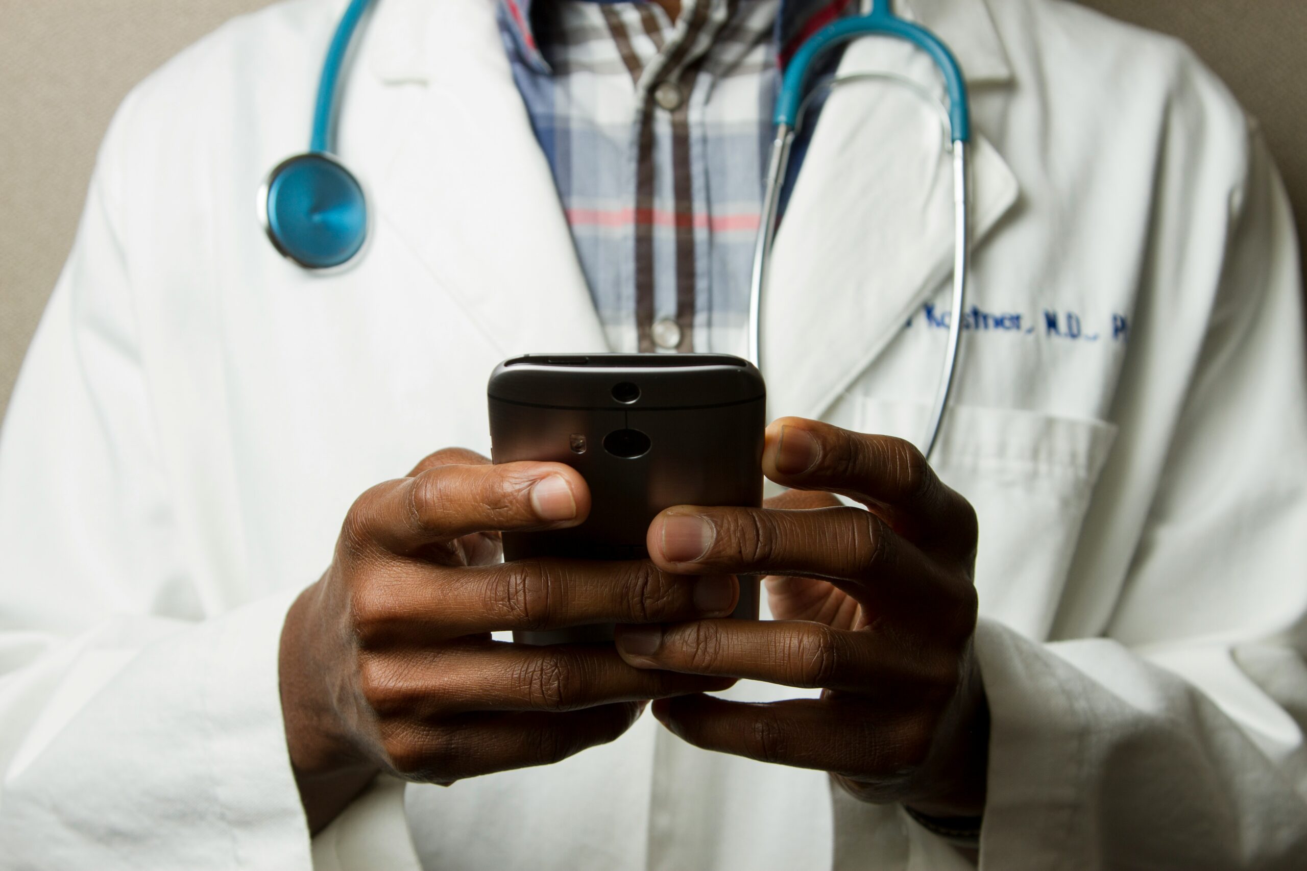 A doctor in a lab quote holds a phone