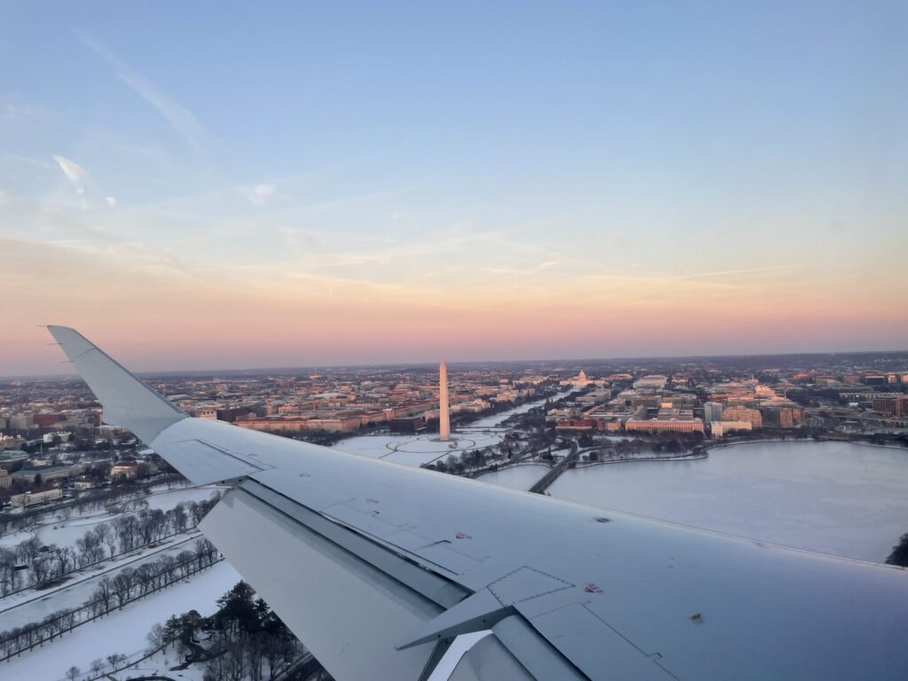 Aerial view from an airplane window of snow covered Washington DC at sunset, with the Washington Monument, the National Mall and the U.S. Capitol
