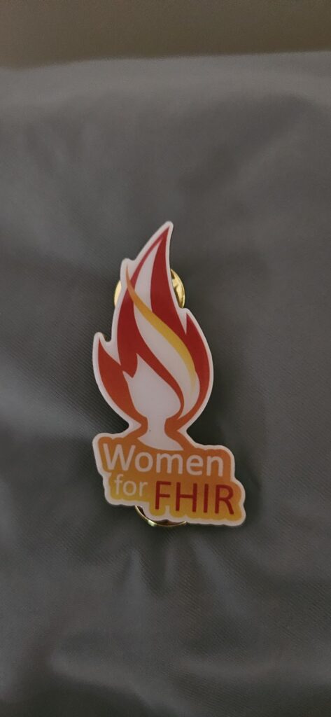 Women for FHIR enamel pin featuring a flame logo